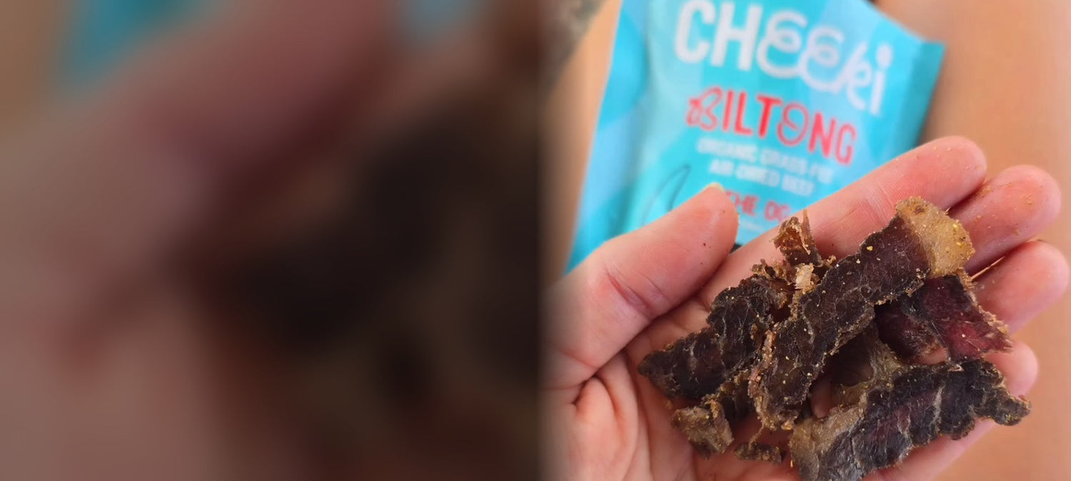 Handful of Cheeki OG biltong slices with the pack behind