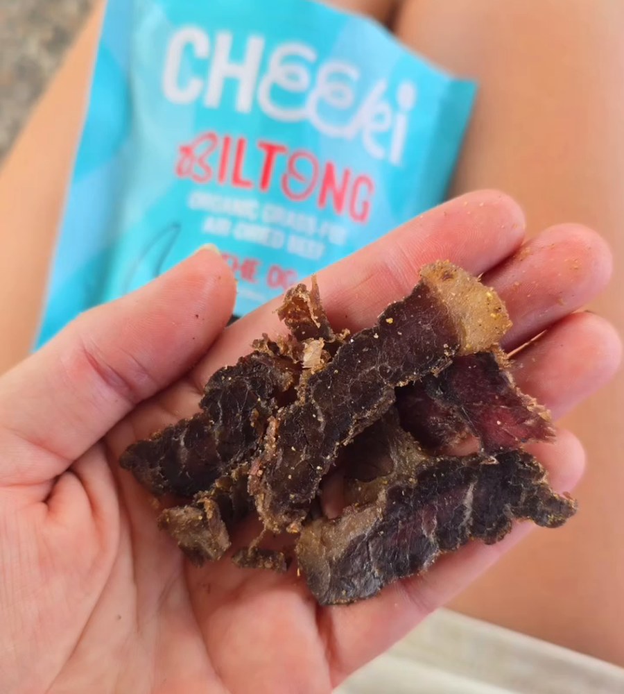 Handful of Cheeki OG biltong slices with the pack behind